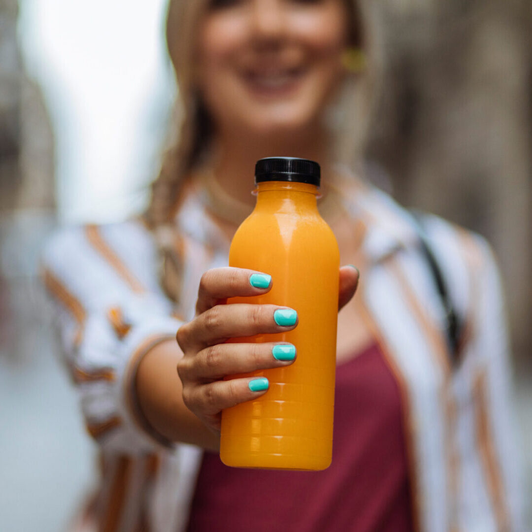 Hand presenting bottled orange drink